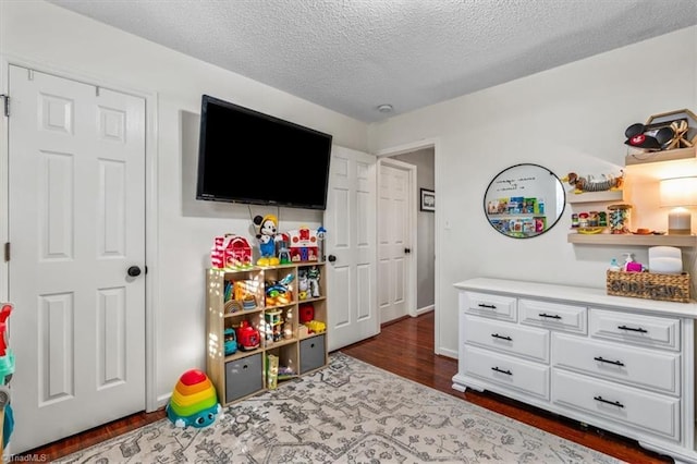 rec room featuring a textured ceiling and dark wood finished floors