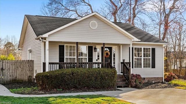 view of front of house featuring a porch, fence, and roof with shingles