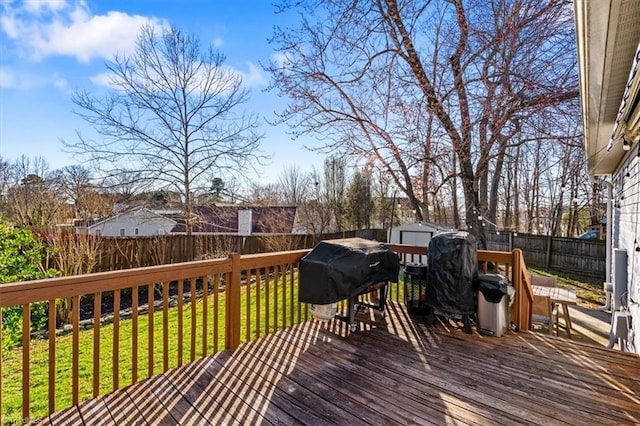 wooden terrace featuring an outbuilding, a shed, a fenced backyard, a lawn, and a grill