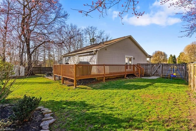 rear view of property featuring a yard, a deck, and a fenced backyard