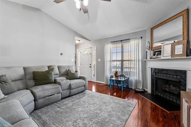 living area featuring a ceiling fan, lofted ceiling, wood finished floors, and a fireplace with raised hearth