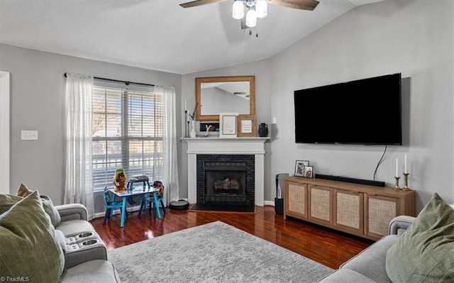 living area featuring a brick fireplace, a ceiling fan, lofted ceiling, and wood finished floors