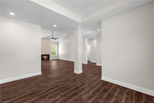 unfurnished living room featuring a ceiling fan, a fireplace, dark wood finished floors, baseboards, and recessed lighting