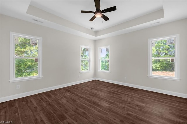spare room featuring baseboards, visible vents, a raised ceiling, and a healthy amount of sunlight
