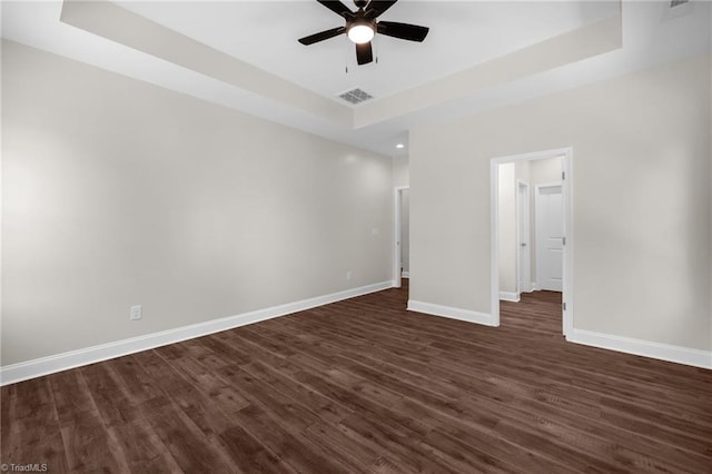 unfurnished bedroom featuring baseboards, dark wood-style flooring, visible vents, and a raised ceiling