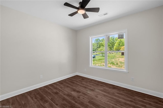 spare room with baseboards, visible vents, dark wood-type flooring, and ceiling fan