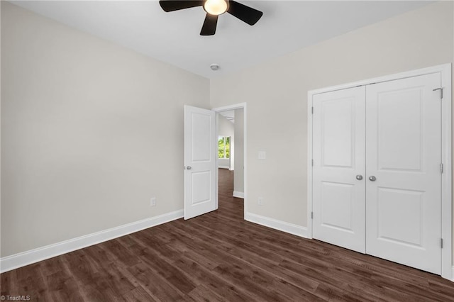 unfurnished bedroom with baseboards, a ceiling fan, dark wood-type flooring, and a closet