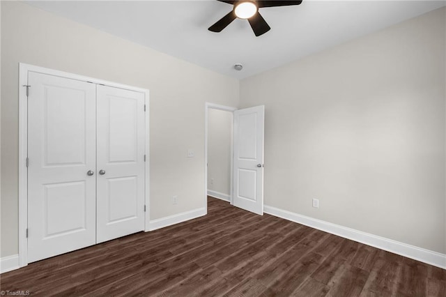 unfurnished bedroom with a ceiling fan, baseboards, dark wood-type flooring, and a closet