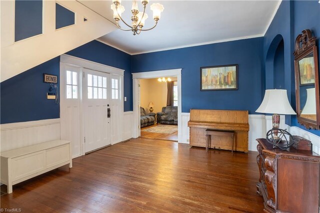 entrance foyer with a chandelier, crown molding, and dark wood-type flooring