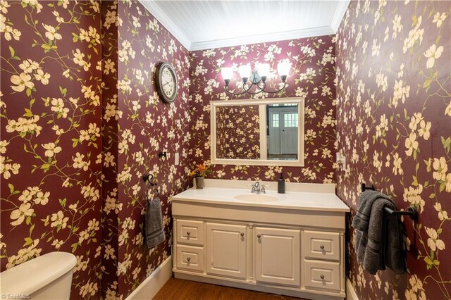 bathroom with vanity, toilet, ornamental molding, and hardwood / wood-style floors