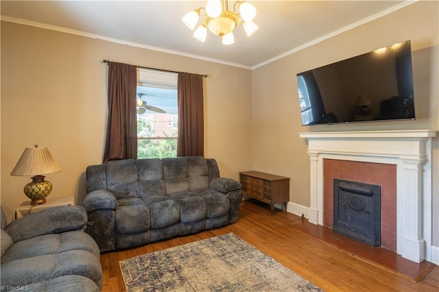 living room with a chandelier, a tiled fireplace, hardwood / wood-style flooring, and crown molding