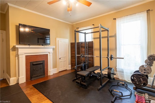 workout area with a fireplace, a wealth of natural light, wood-type flooring, and ceiling fan