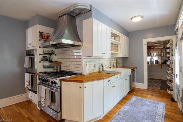 kitchen featuring stainless steel range, white cabinetry, light hardwood / wood-style flooring, and butcher block countertops