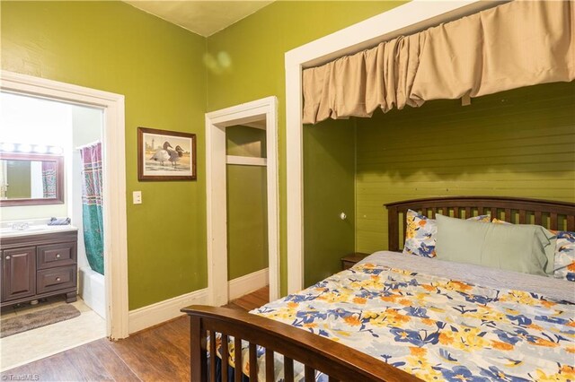 bedroom with ensuite bath, sink, and dark hardwood / wood-style floors