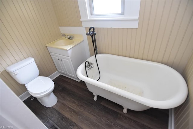 bathroom with hardwood / wood-style floors, vanity, toilet, and a tub to relax in