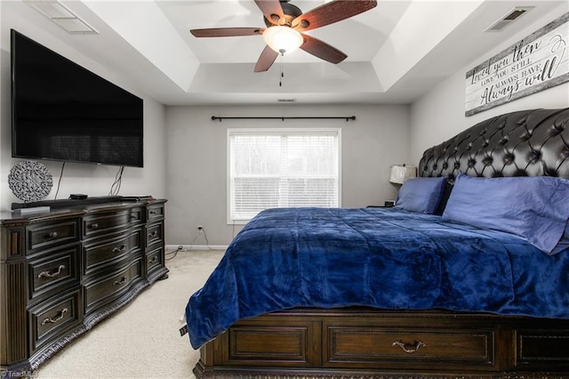 bedroom featuring ceiling fan, light carpet, and a tray ceiling