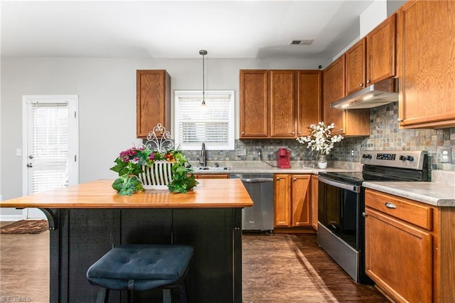 kitchen with sink, hanging light fixtures, dark hardwood / wood-style floors, a kitchen bar, and appliances with stainless steel finishes