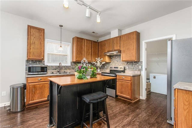 kitchen featuring appliances with stainless steel finishes, tasteful backsplash, dark wood-type flooring, sink, and decorative light fixtures