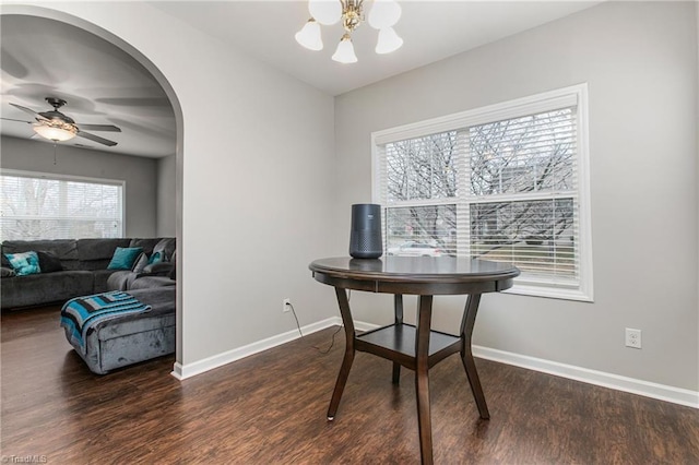 dining area with ceiling fan with notable chandelier and dark hardwood / wood-style flooring