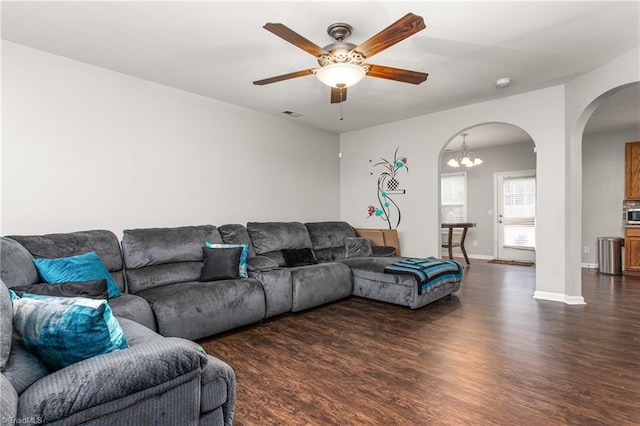 living room with ceiling fan with notable chandelier and dark wood-type flooring