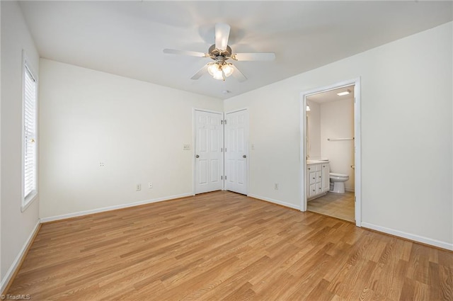 unfurnished bedroom featuring baseboards, ensuite bathroom, a ceiling fan, and light wood finished floors
