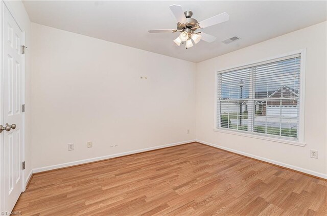 spare room with light wood-style floors, baseboards, ceiling fan, and visible vents