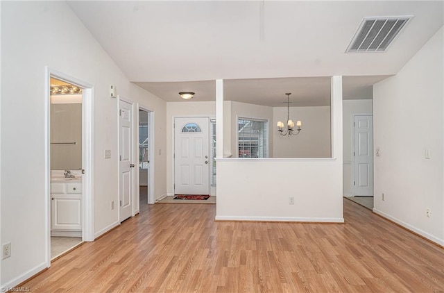 interior space with a notable chandelier, a sink, baseboards, light wood-type flooring, and visible vents