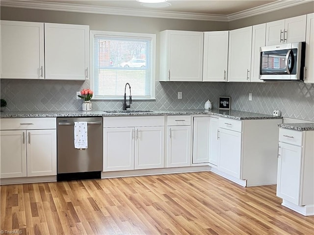 kitchen with stone countertops, white cabinetry, sink, ornamental molding, and stainless steel appliances