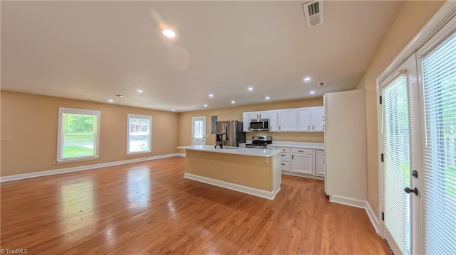 2209 Bracyridge Rd, Greensboro, NC 27407 - kitchen with stainless steel appliances, open floor plan, a kitchen island with sink, baseboards, and white cabinetry