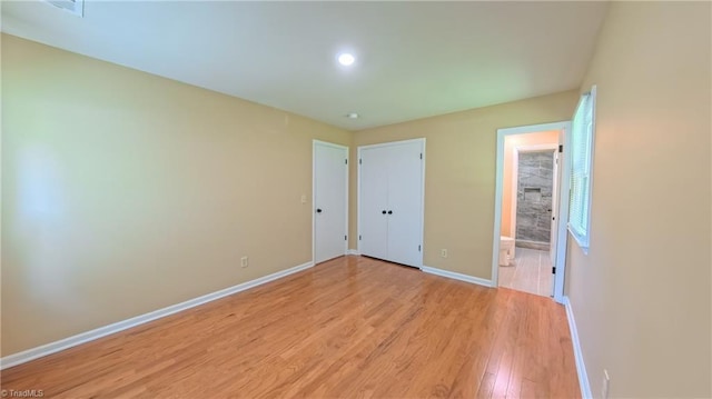 2209 Bracyridge Rd, Greensboro, NC 27407 - unfurnished bedroom with baseboards, light wood-style floors, and connected bathroom
