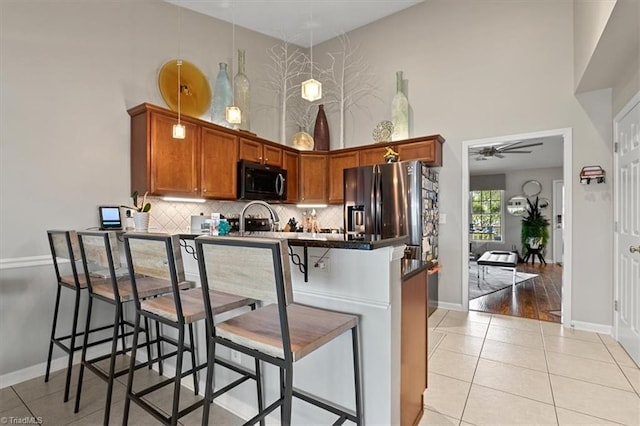 kitchen featuring a breakfast bar, light wood-type flooring, kitchen peninsula, ceiling fan, and stainless steel refrigerator with ice dispenser