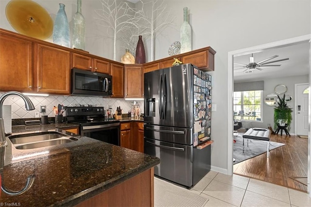 kitchen featuring black appliances, ceiling fan, tasteful backsplash, dark stone countertops, and light hardwood / wood-style floors