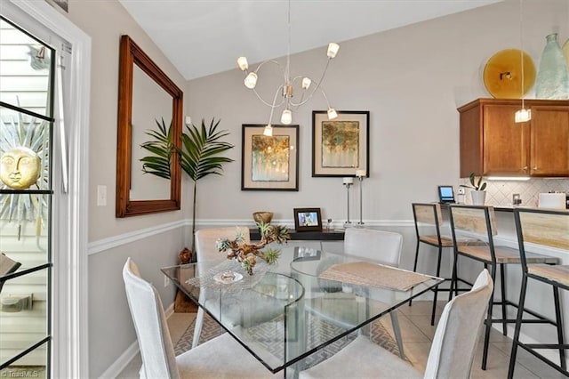 dining area featuring tile patterned flooring, vaulted ceiling, and an inviting chandelier