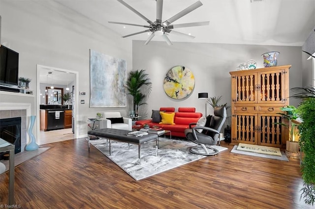 living room with a fireplace, hardwood / wood-style flooring, vaulted ceiling, and ceiling fan