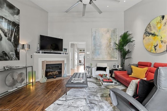 living room with a tile fireplace, hardwood / wood-style flooring, and ceiling fan