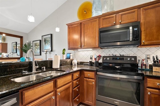 kitchen featuring lofted ceiling, dark stone countertops, appliances with stainless steel finishes, decorative light fixtures, and sink