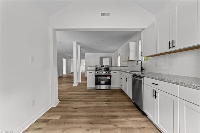 301 Rockspring Rd, High Point, NC 27262 - kitchen with appliances with stainless steel finishes, light stone counters, white cabinets, decorative backsplash, and lofted ceiling