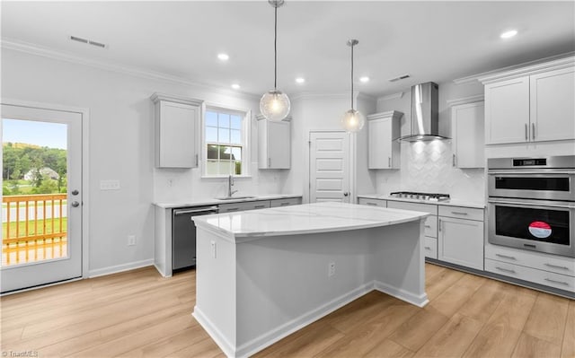 700 Fairmile Dr, Greensboro, NC 27455 - kitchen featuring appliances with stainless steel finishes, a sink, wall chimney range hood, light wood-style floors, and crown molding