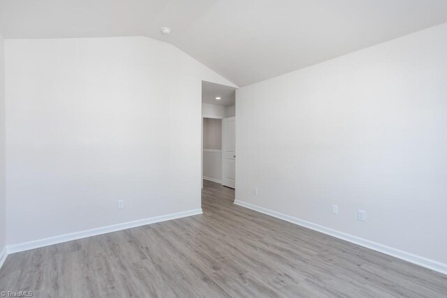 empty room featuring light hardwood / wood-style floors and vaulted ceiling