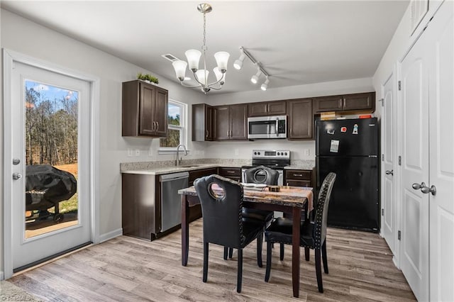 kitchen with hanging light fixtures, dark brown cabinetry, appliances with stainless steel finishes, and a sink