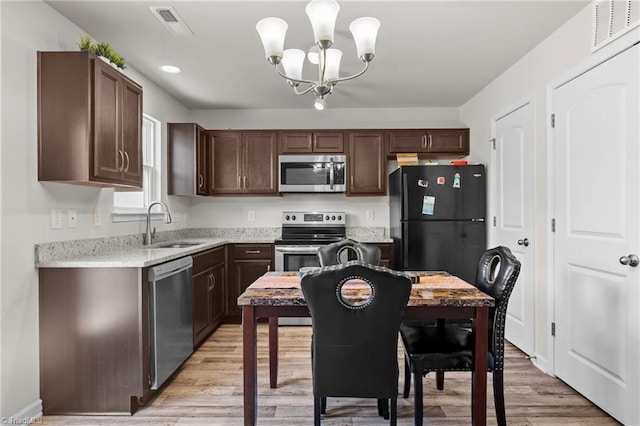 kitchen featuring dark brown cabinets, appliances with stainless steel finishes, a sink, and light wood-style flooring