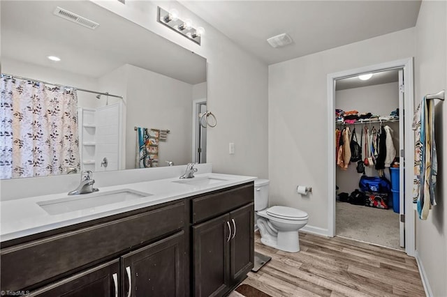 full bathroom with wood finished floors, visible vents, a sink, and double vanity