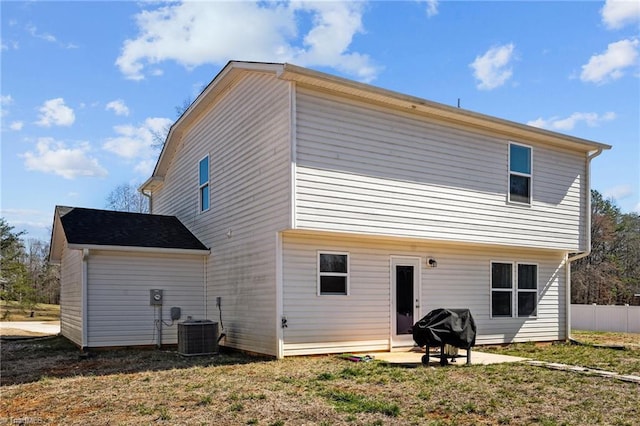 rear view of property with central air condition unit, a patio area, fence, and a lawn