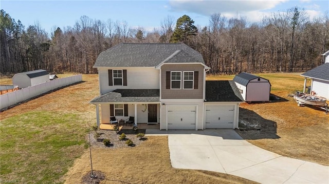 traditional home featuring a porch, fence, concrete driveway, a storage unit, and a front yard