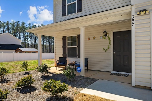 entrance to property with a porch and fence