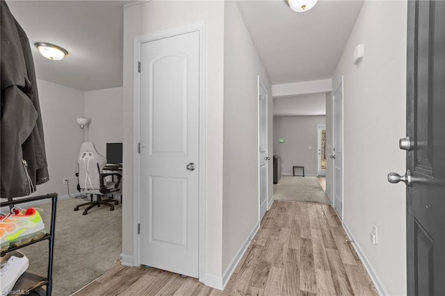 hallway featuring light wood-style floors and baseboards