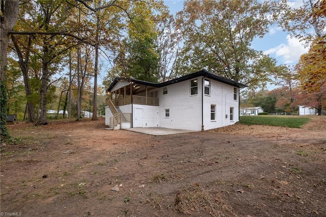 view of side of property featuring a patio area and a sunroom