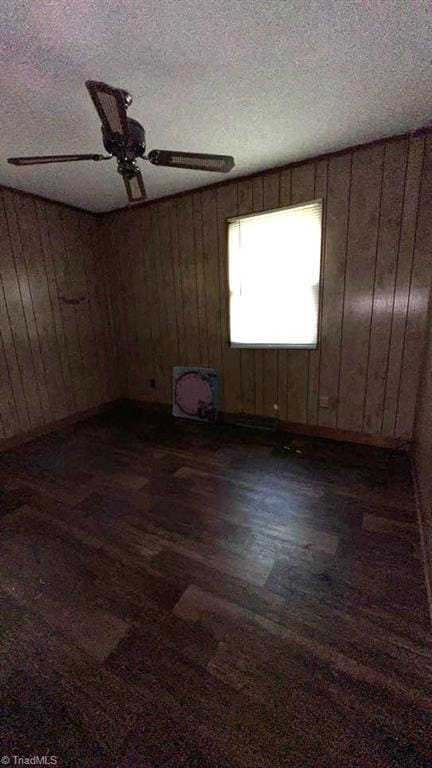 225 Dan Bryant Rd, Pilot Mountain, NC 27041 - unfurnished room featuring dark wood-style flooring, ceiling fan, wooden walls, and a textured ceiling