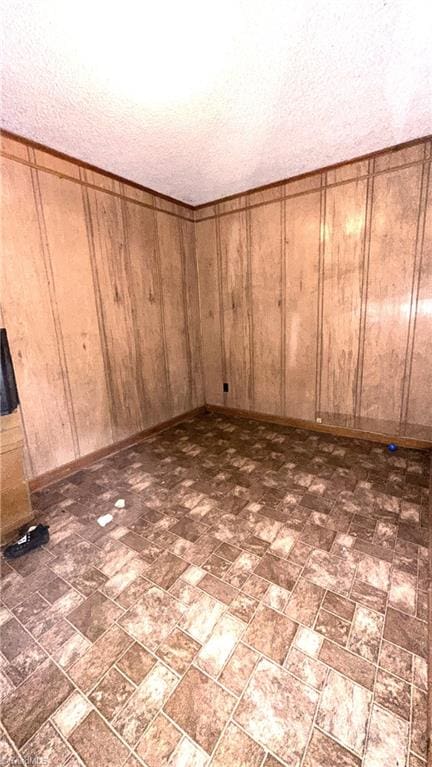 225 Dan Bryant Rd, Pilot Mountain, NC 27041 - unfurnished bedroom with brick patterned floors, wooden walls, a textured ceiling, and baseboards