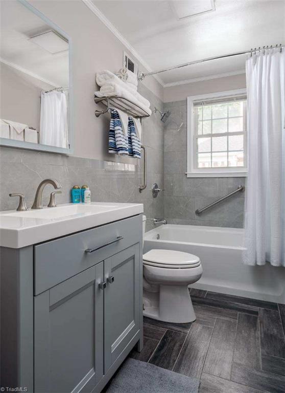 3006 Collier Dr, Greensboro, NC 27403 - full bathroom with vanity, shower / bathtub combination with curtain, ornamental molding, and tile walls